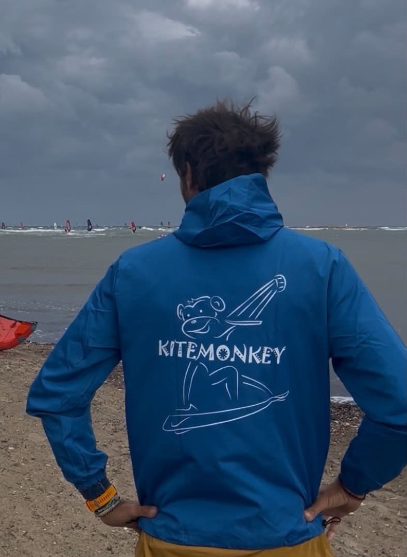 Kitemonkey windproof kitesurf jacket in electric blue worn after a kitesurf session on the beach
